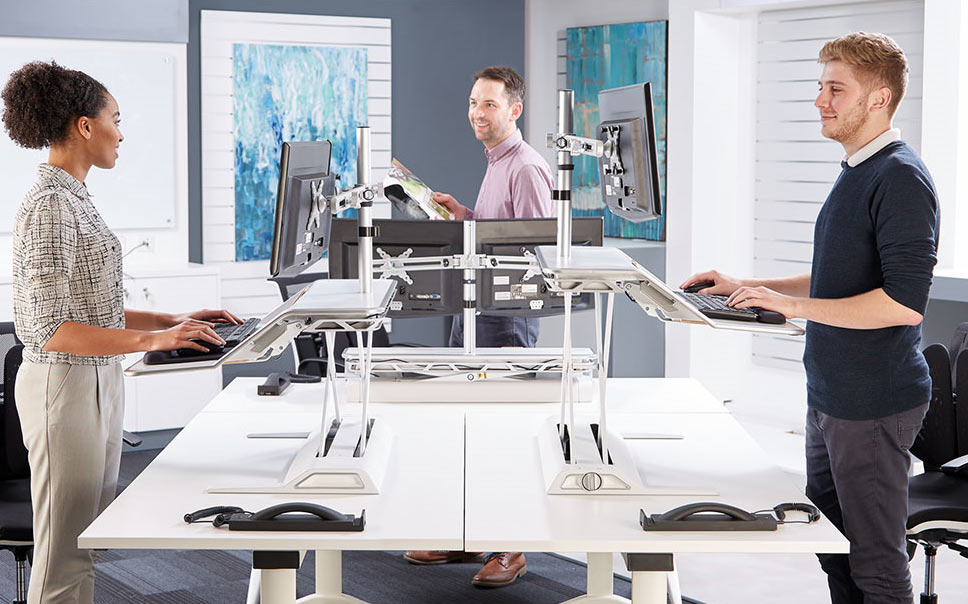 Lifestyle image showing employees using the Lotus Sit-Stand Workstation in an office environment